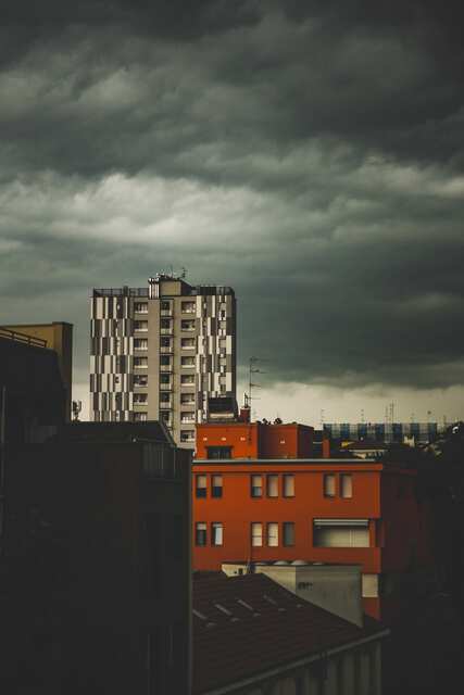 Dark storm clouds hanging low over rows of town buildings during heavy rain