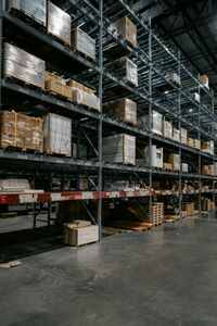 Rows of stacked shelving loaded with wrapped pallets and boxes inside an industrial warehouse